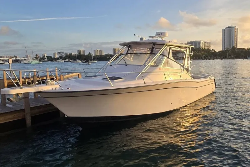 The Image of 2003 Grady-White Express 330 boat docked at sunset with city skyline backdrop. - 1