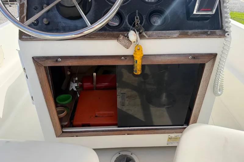 Slide: The Image of 1988 Wahoo 1850 boat dashboard with steering wheel and storage compartment. - 19