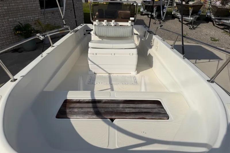 Slide: The Image of 1988 Wahoo 1850 boat interior with seating and steering console, docked outdoors. - 13
