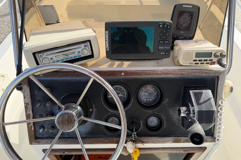 Slide: The Image of 1988 Wahoo 1850 boat dashboard with steering wheel, gauges, and electronic devices. - 18