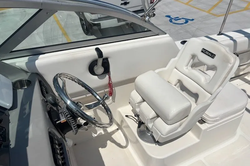 Slide: The Image of 2009 Robalo R227 Dual Console boat interior with steering wheel and white captain's chair. - 9