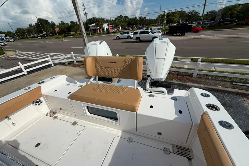 Slide: The Image of 2027 Caymas 29 CT boat with tan seating and dual outboard motors, parked near a road. - 7