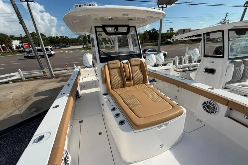 Slide: The Image of 2027 Caymas 29 CT boat with tan seating, docked in a marina under clear skies. - 13