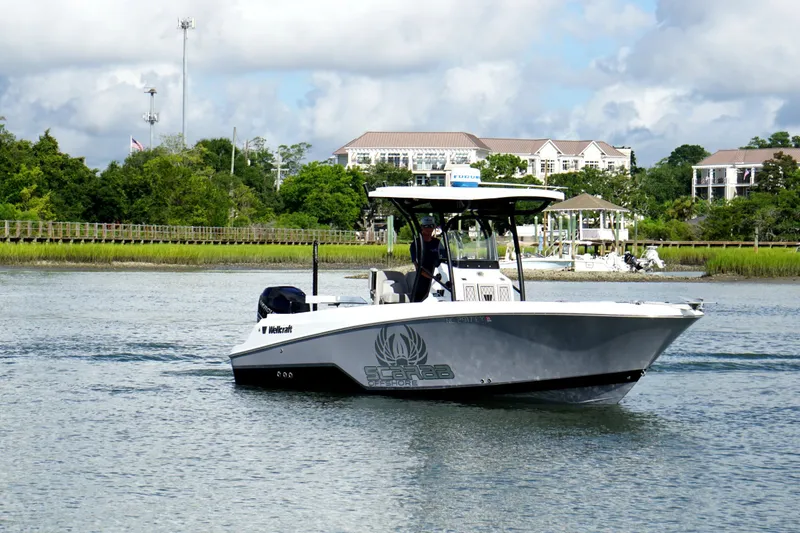 Slide: The Image of 2022 Wellcraft 242 Scarab Offshore boat cruising on a scenic waterway with lush greenery. - 3