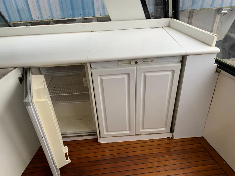 Slide: The Image of 1991 TransWorld Cockpit Motoryacht interior with open mini fridge and wooden flooring. - 28