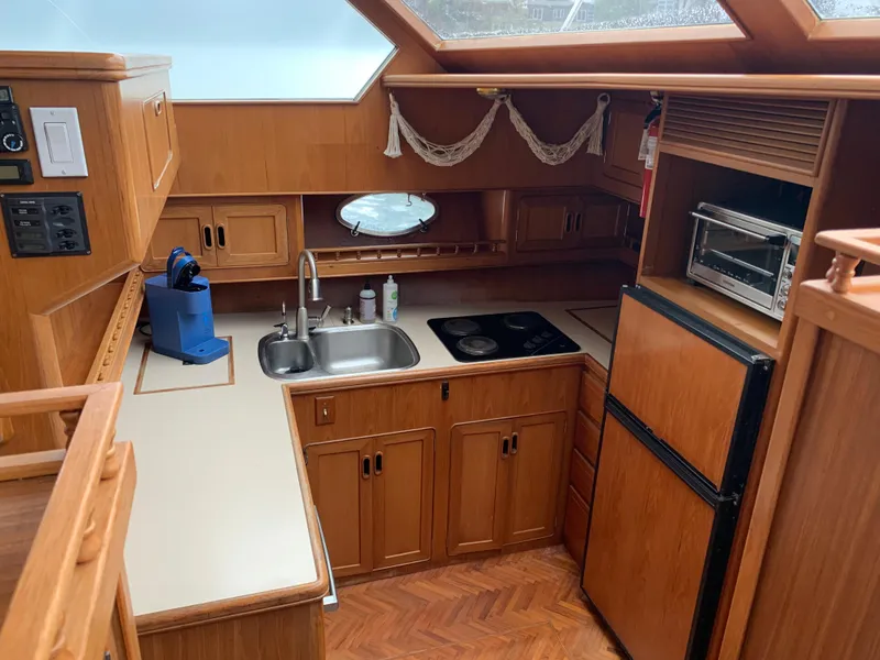 Slide: The Image of 1991 TransWorld Cockpit Motoryacht kitchen with wooden cabinets, sink, stove, and refrigerator. - 24