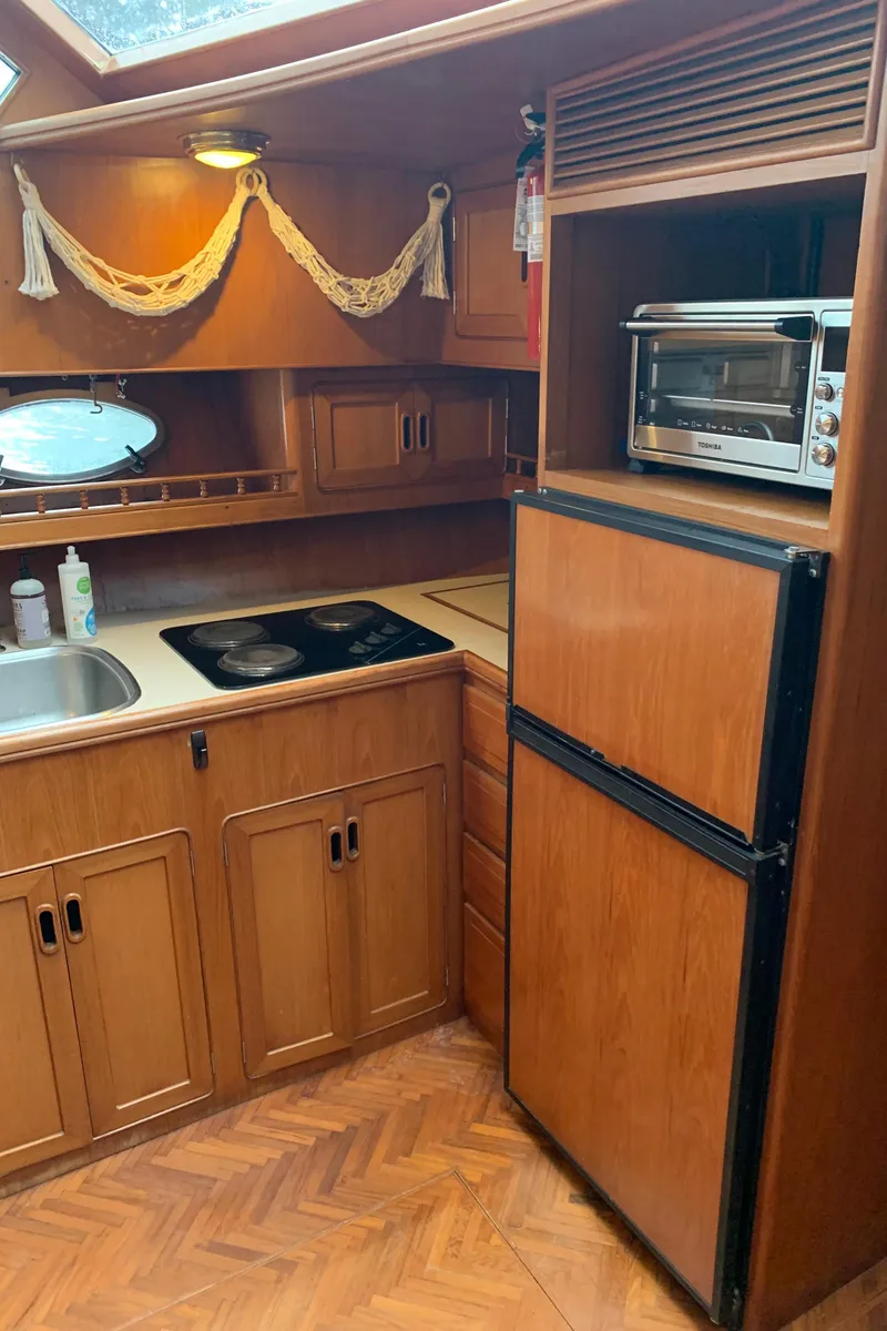 Slide: The Image of 1991 TransWorld Cockpit Motoryacht kitchen with wood cabinets, fridge, and stove. - 34