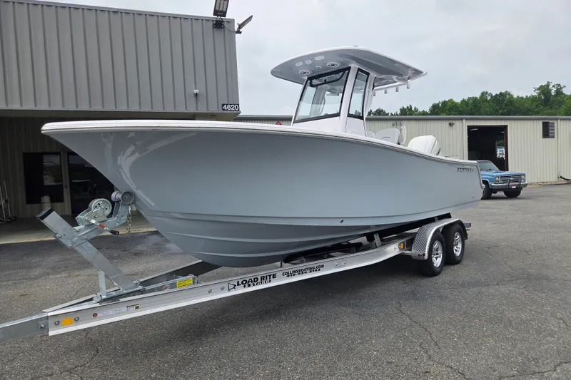 Slide: The Image of 2026 Sportsman Open 232 Center Console boat on trailer outside a warehouse. - 1