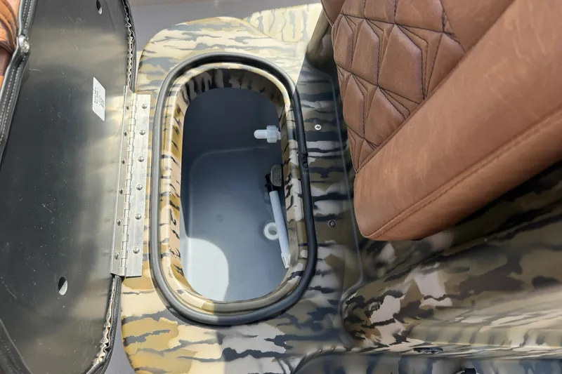 Slide: The Image of Camouflage-patterned storage compartment in 2027 Avid 20 Rogue CC boat with brown leather seat. - 14