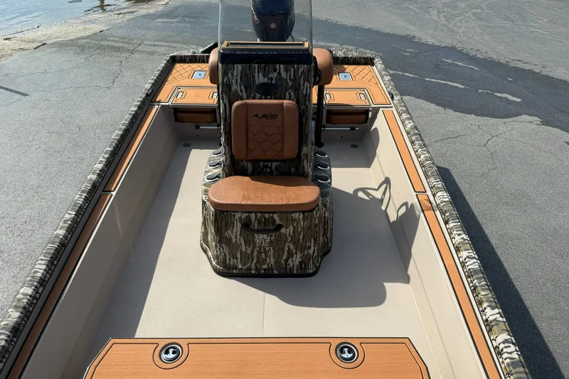 Slide: The Image of 2027 Avid 20 Rogue CC boat with camo design and tan seating, docked on pavement. - 18