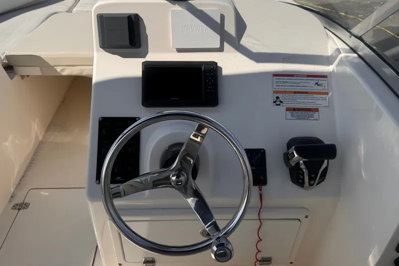 Slide: The Image of 2023 Cobia 220 Dual Console boat helm with steering wheel and controls. - 9