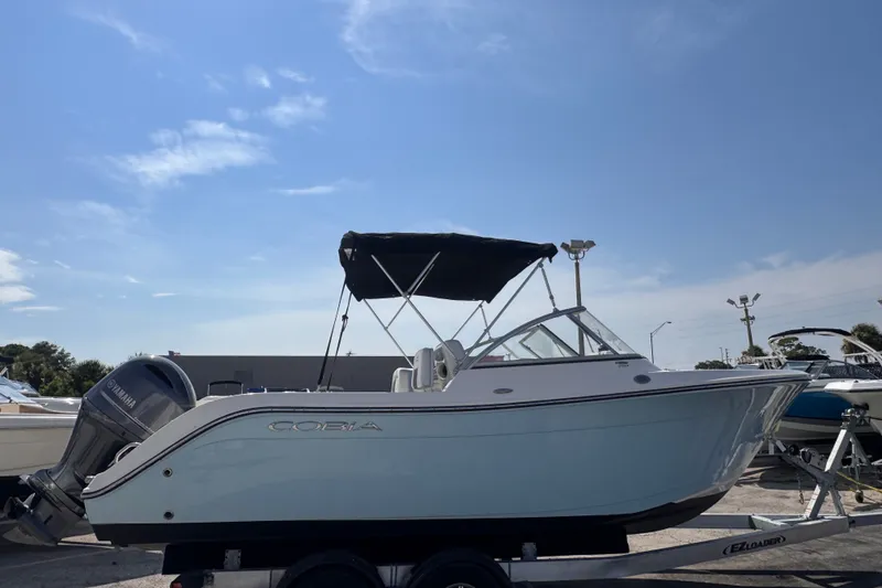 Slide: The Image of 2023 Cobia 220 Dual Console boat on trailer under clear sky. - 2
