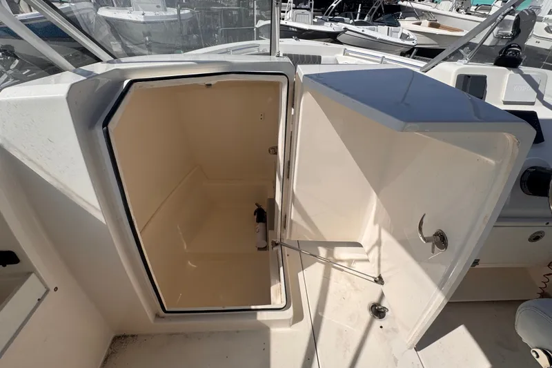 Slide: The Image of 2023 Cobia 220 Dual Console boat storage compartment open, showcasing interior space. - 12
