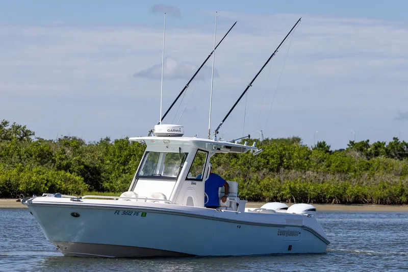 Slide: The Image of 2011 Everglades 295 Center Console boat on calm water, featuring fishing rods and lush greenery. - 18