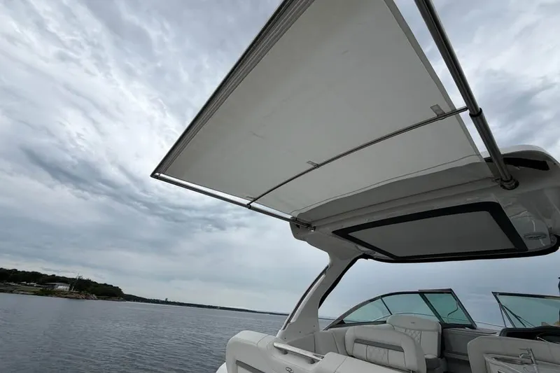 Slide: The Image of 2025 Regal 33 Express boat with canopy, on a calm lake under cloudy skies. - 3