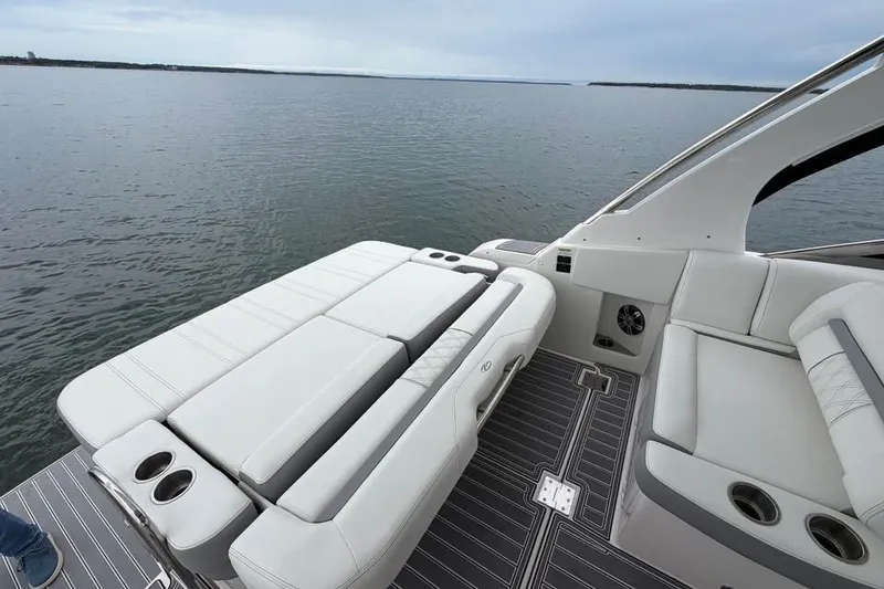 Slide: The Image of 2025 Regal 33 Express boat interior with luxurious seating and cup holders on calm water. - 6