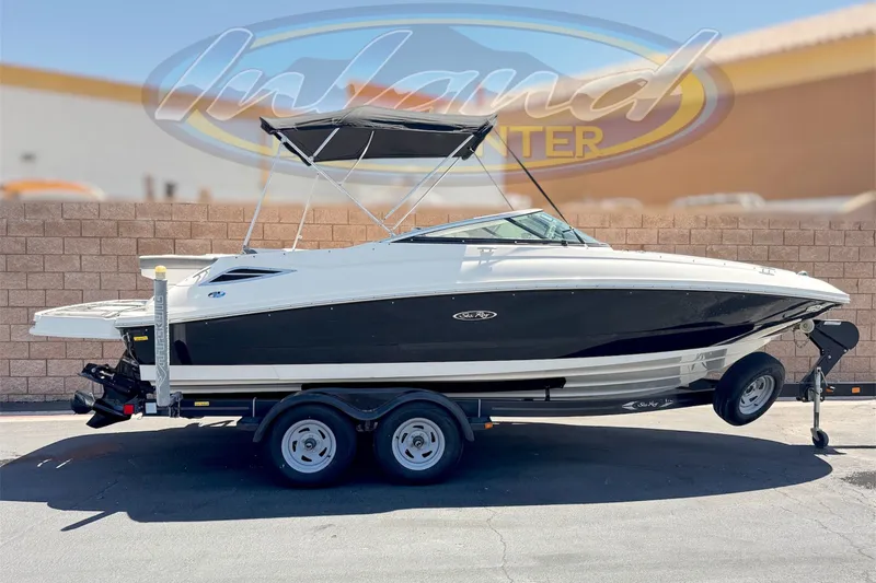 The Image of 2013 Sea Ray 220 Sundeck boat on trailer, parked outdoors with bimini top. - 0