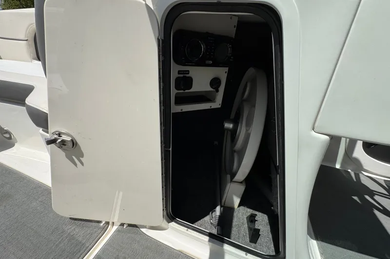 Slide: The Image of 2013 Sea Ray 220 Sundeck storage compartment with open door and visible interior. - 34