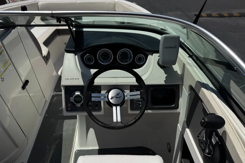 Slide: The Image of 2013 Sea Ray 220 Sundeck boat cockpit with steering wheel and Garmin device. - 30