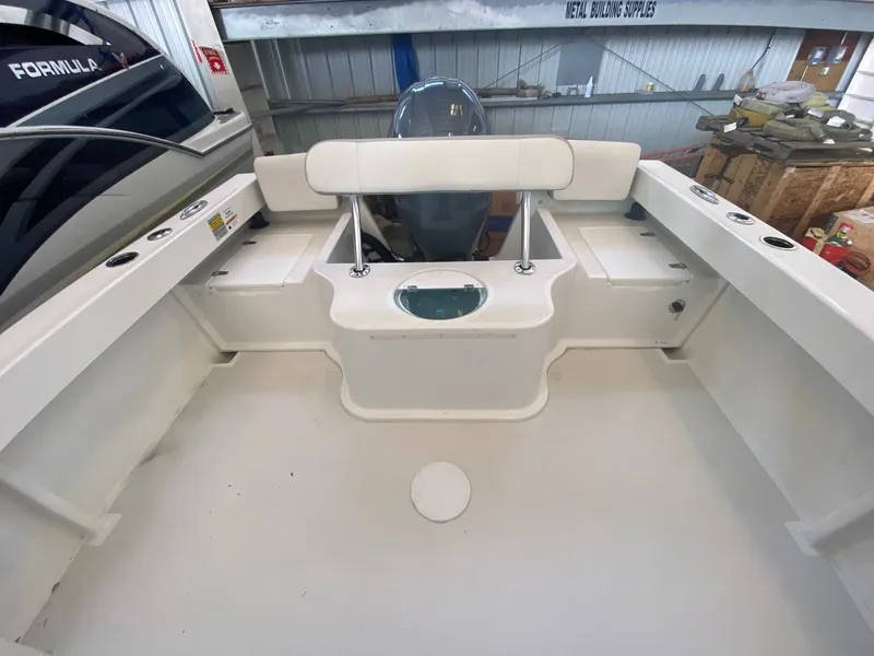 Slide: The Image of The image shows the cockpit of a 2022 Parker 2120 Sport Cabin boat. It features a clean, white surface with a central seating area and an engine in the background. - 11