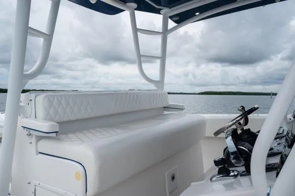 Slide: The Image of 2016 SeaHunter 45 Tournament boat interior with white seating and steering wheel, on a cloudy day. - 22