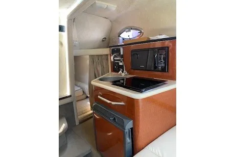 Slide: The Image of 2004 Sea Ray 240 Sundancer cabin interior with kitchenette and compact appliances. - 11