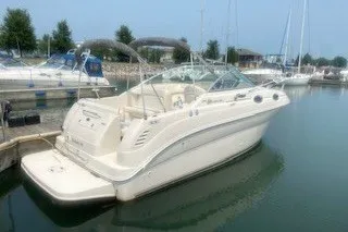 Slide: The Image of 2004 Sea Ray 240 Sundancer boat docked in a marina, featuring sleek design and spacious deck. - 7