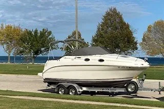 Slide: The Image of 2004 Sea Ray 240 Sundancer boat on trailer by lakeside, clear sky background. - 5