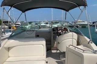 Slide: The Image of 2004 Sea Ray 240 Sundancer boat interior with helm, seating, and canopy at marina. - 8
