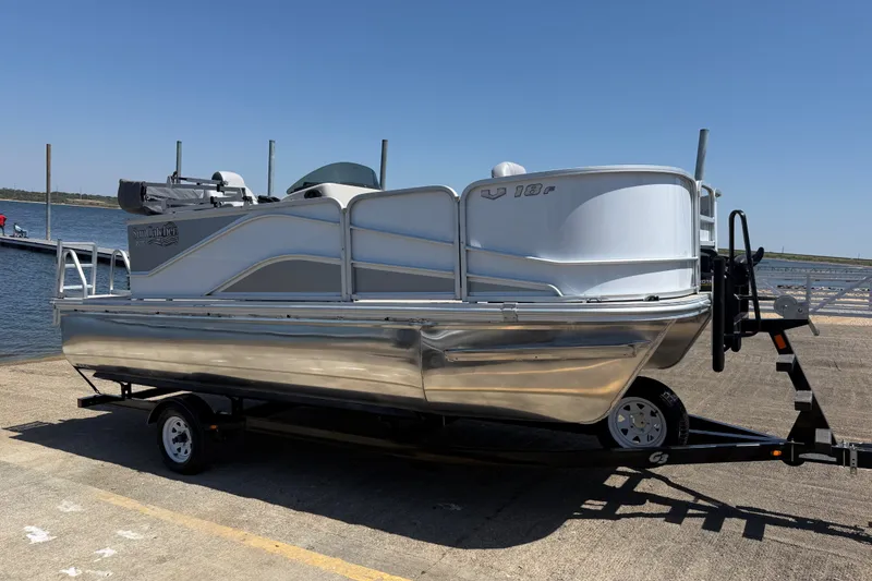 Slide: The Image of 2020 SunCatcher V18 Fish pontoon boat on trailer by the water. - 2