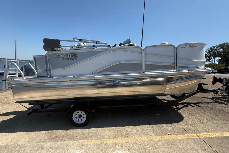 Slide: The Image of 2020 SunCatcher V18 Fish pontoon boat on trailer, parked outdoors under clear sky. - 3