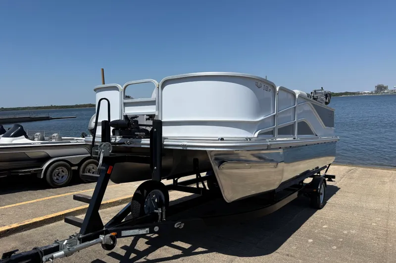 Slide: The Image of 2020 SunCatcher V18 Fish boat on trailer by the water, clear sky background. - 18