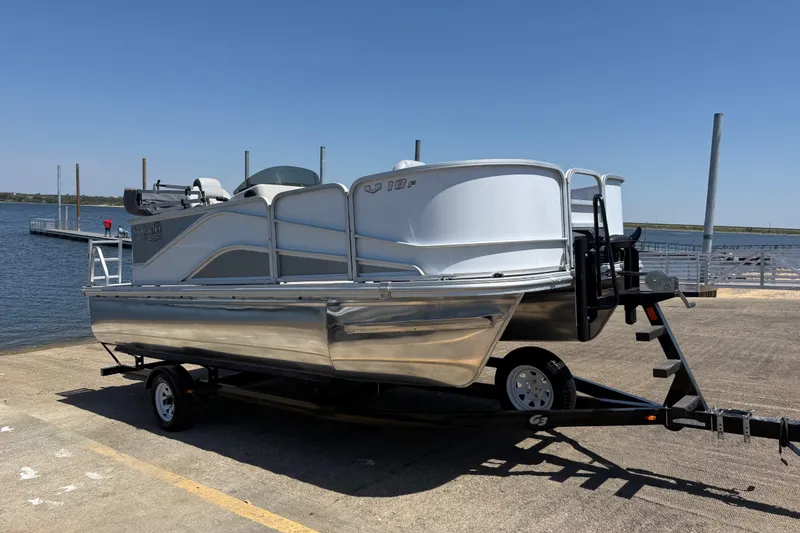 Slide: The Image of 2020 SunCatcher V18 Fish boat on trailer by a lakeside dock. - 1