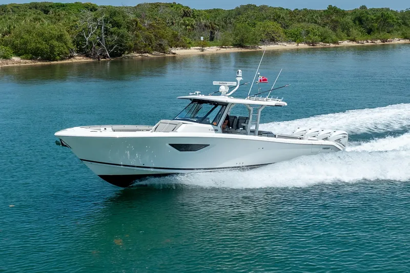 Slide: The Image of 2022 Pursuit S 428 Sport boat cruising on clear blue water near a lush shoreline. - 18