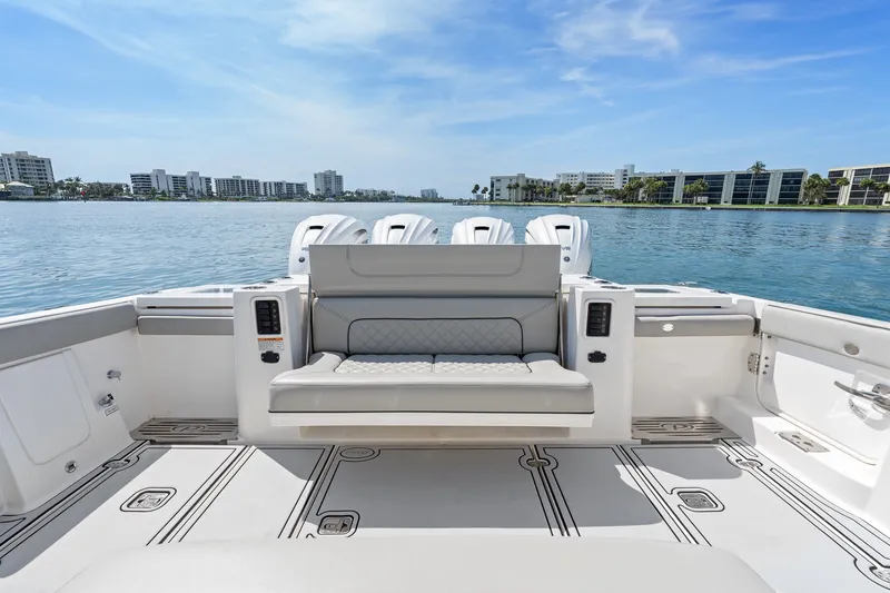 Slide: The Image of 2022 Pursuit S 428 Sport boat interior with seating, overlooking calm waters and cityscape. - 32