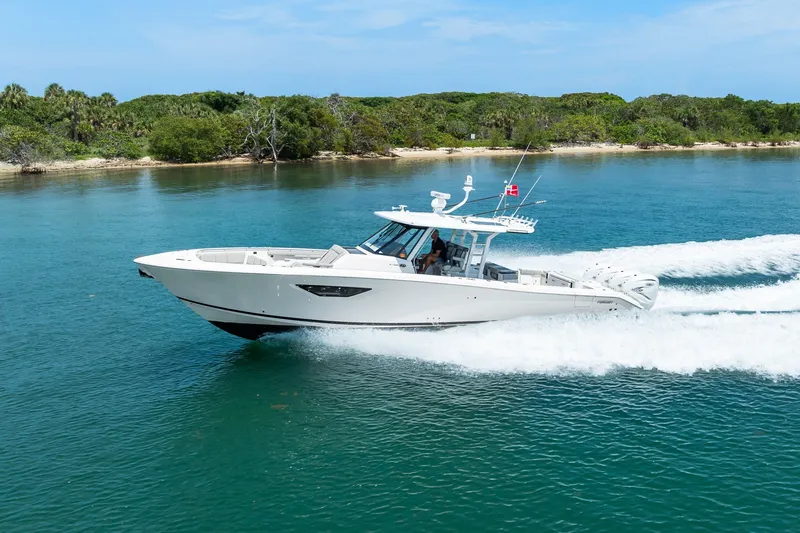 Slide: The Image of 2022 Pursuit S 428 Sport boat cruising on clear blue water near a lush shoreline. - 19