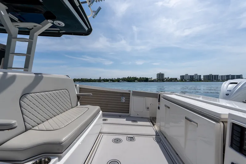 Slide: The Image of 2022 Pursuit S 428 Sport boat interior with luxurious seating, overlooking a scenic waterfront. - 30