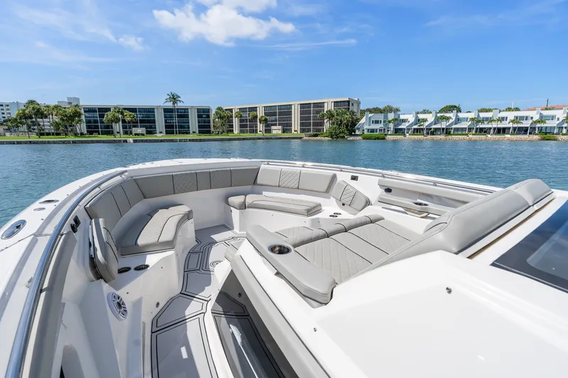 Slide: The Image of 2022 Pursuit S 428 Sport boat interior with luxurious seating, docked near waterfront homes. - 43