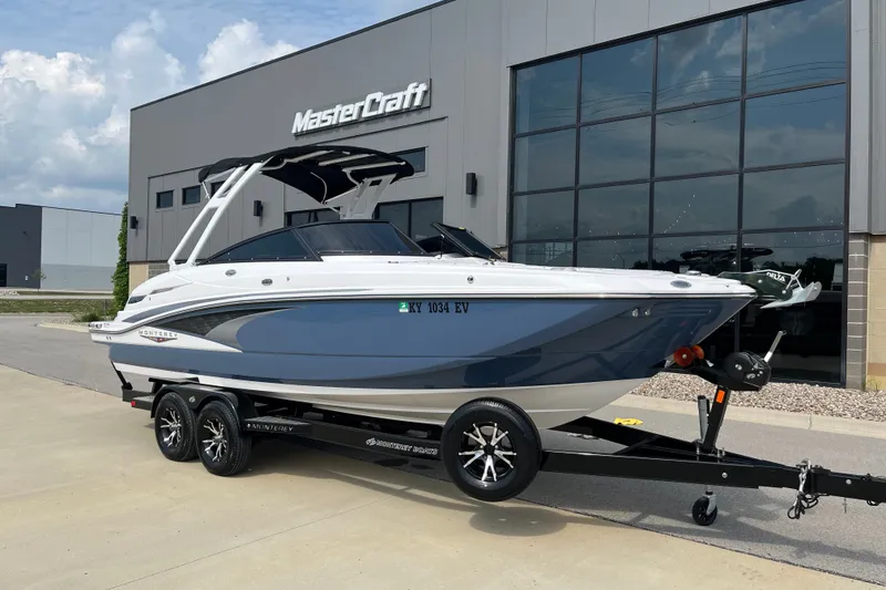 The Image of 2025 Monterey M6 boat on trailer outside MasterCraft building, showcasing sleek design. - 1