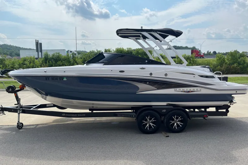 Slide: The Image of 2025 Monterey M6 boat on trailer, sleek design, parked outdoors under cloudy sky. - 6