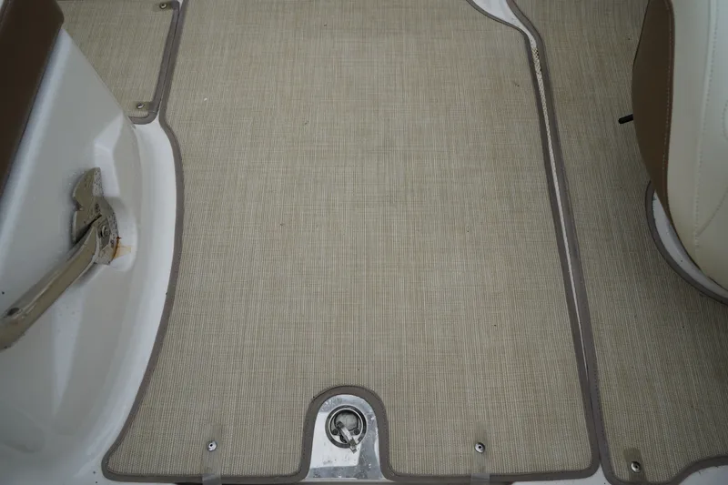 Slide: The Image of Interior flooring of a 2015 Chaparral 230 Suncoast boat, featuring beige carpet and metal fixtures. - 9