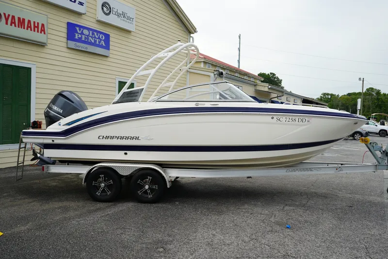 The Image of 2015 Chaparral 230 Suncoast boat on trailer, parked outside dealership. - 1