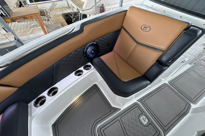 Slide: The Image of 2021 Cobalt R8 Surf boat interior with tan and black seating, cup holders, and speaker. - 24