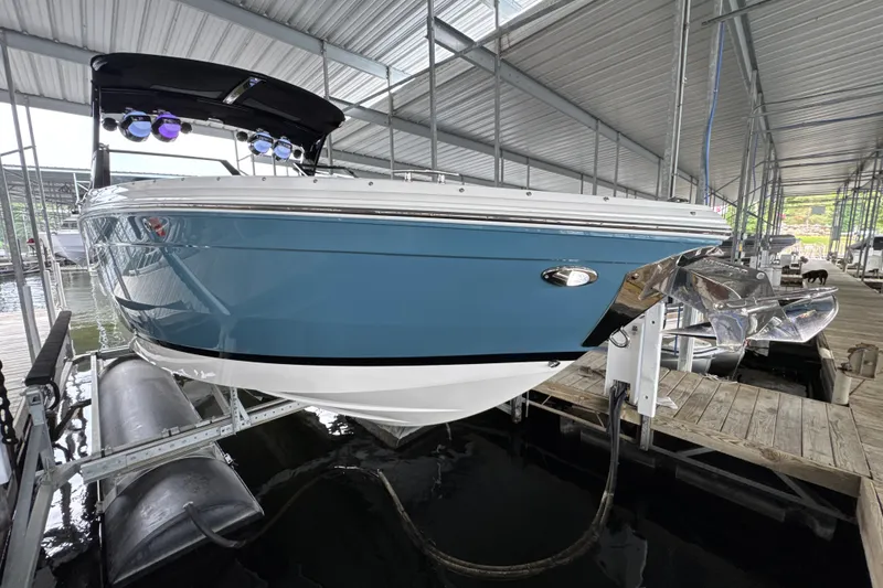 Slide: The Image of 2021 Cobalt R8 Surf boat in dock, blue hull, covered marina setting. - 2