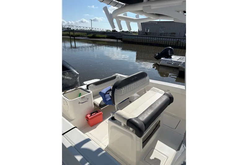 Slide: The Image of 2023 Trophy CC24 boat interior with seating and storage, docked by a calm waterway. - 8
