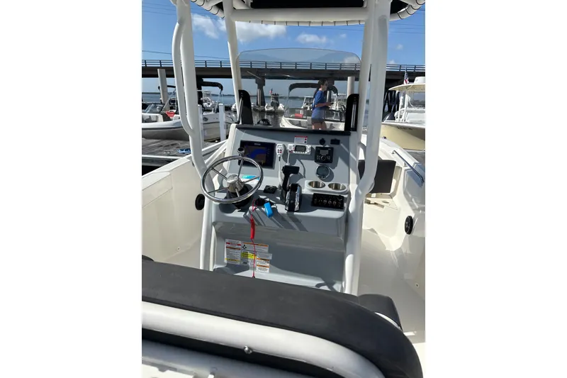 Slide: The Image of 2023 Trophy CC24 boat interior with steering wheel and control panel, docked under a bridge. - 3