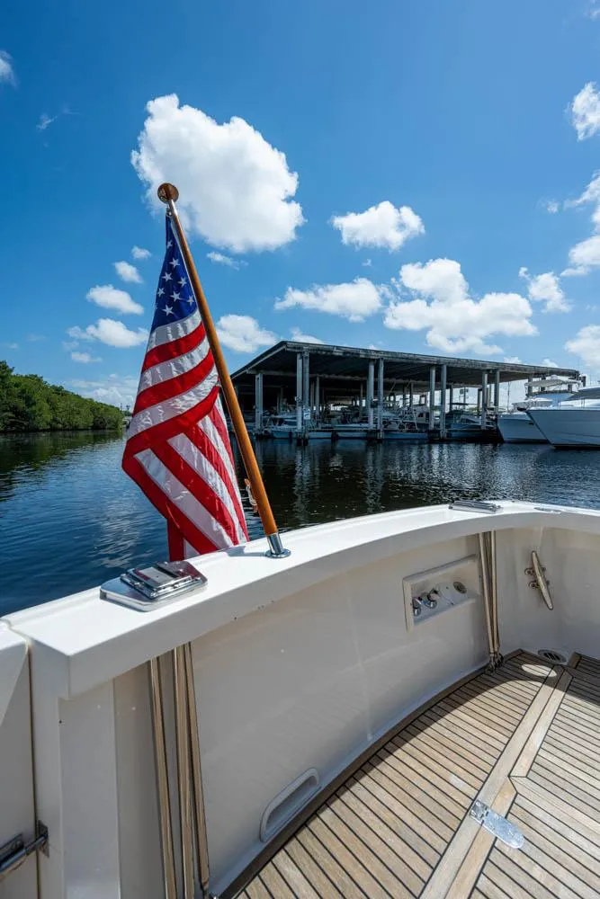 Slide: The Image of Aft view of a 2007 Grand Banks 43 Eastbay SX with an American flag and marina in the background. - 20