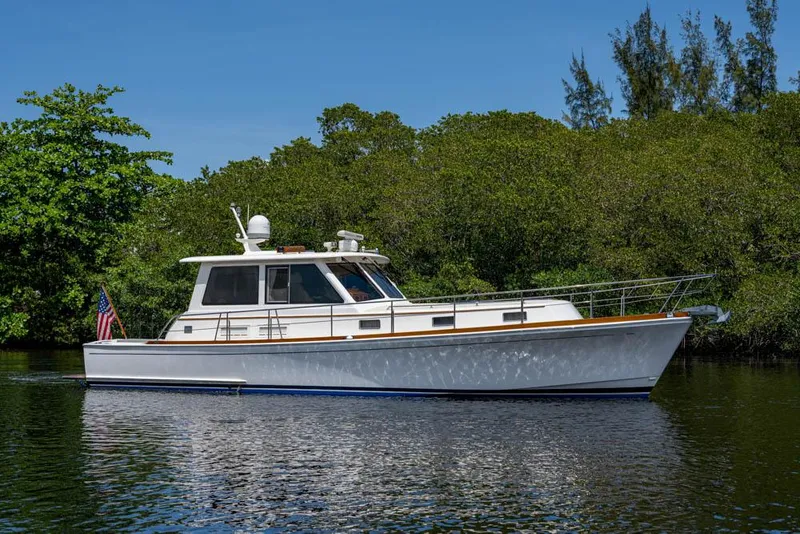 Slide: The Image of 2007 Grand Banks 43 Eastbay SX on calm water with a lush green backdrop. - 5