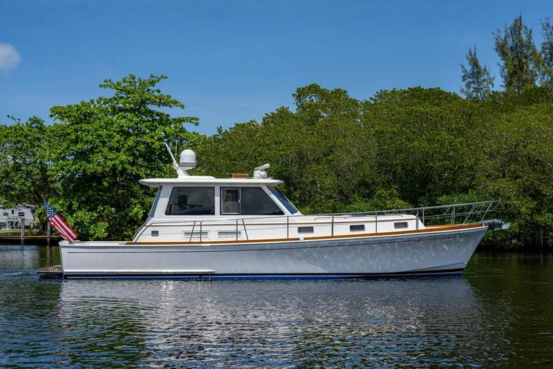 Slide: The Image of 2007 Grand Banks 43 Eastbay SX on calm water, surrounded by lush greenery. - 47