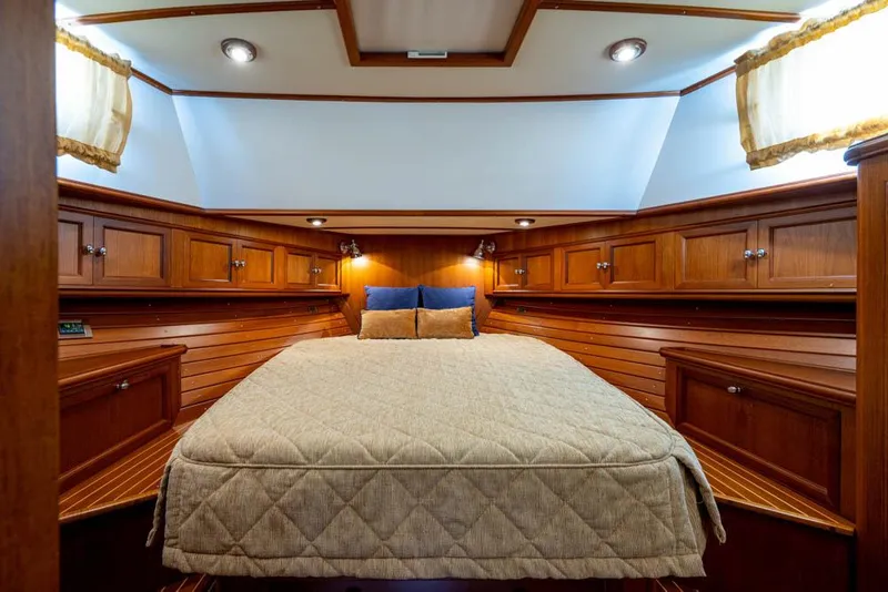 Slide: The Image of The cabin of the 2007 Grand Banks 43 Eastbay SX features a large bed with wooden walls and cabinets. - 36